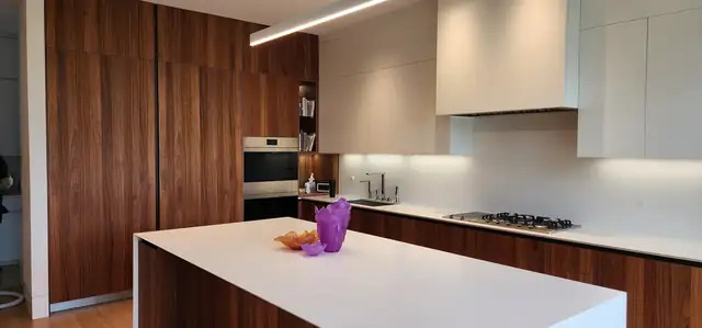 Modern kitchen with walnut tall cabinets, white lacquer uppers and a white quartz island