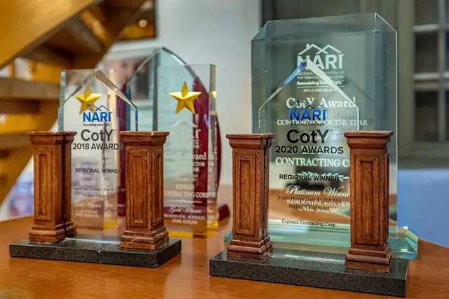 NARI Contractor of the Year award trophies won by Elite Kitchen & Bath, displayed on a wooden table