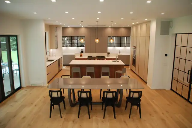 Whole-floor renovation with a long dining table facing an open kitchen with two islands and wood flooring