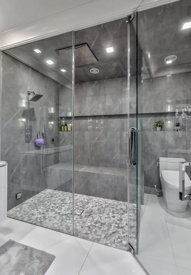 Great Neck, NY master bath with a curbless steam shower, gray large-format tile and pebble shower floor